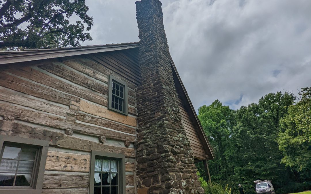 Beautiful stone chimney attached to a log cabin